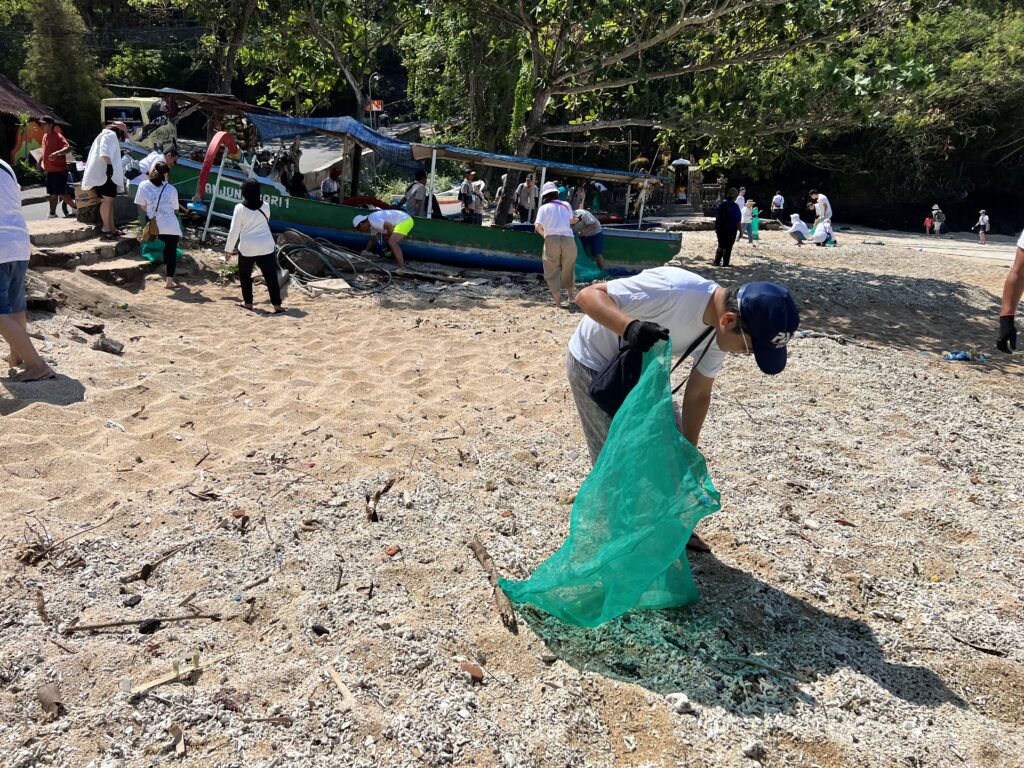 sekumpulan orang berbaju putih mengutip sampah pada acara beach cleanup
