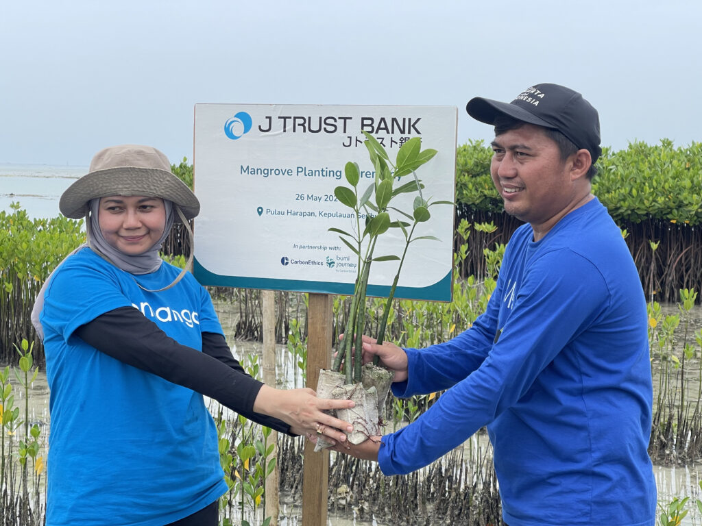 petani mangrove memegang bibit mangrove dengan perwakilan karyawan J Trust Bank untuk upaya sustainability perusahaan