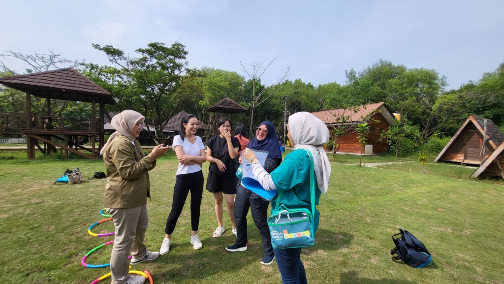 4 wanita peserta games outing kantor bermain game Terdampar sambil tertawa di lapangan hijau