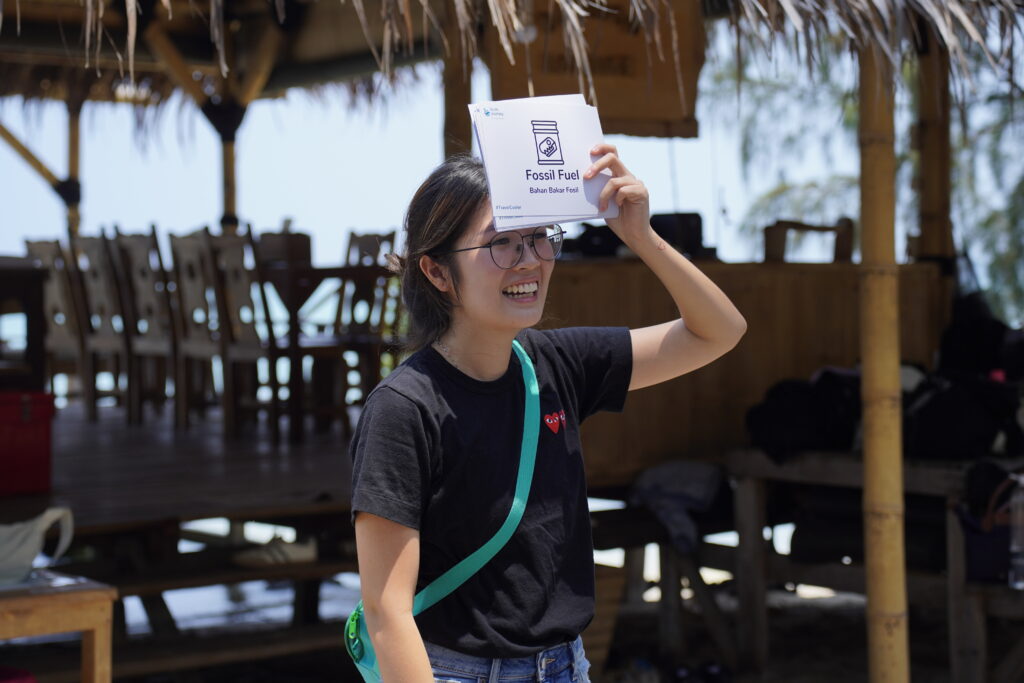 peserta outing kantor Bumi Journey berbaju hitam memegang kartu indeks dalam permainan tebak gaya di depan lounge Desa Laguna